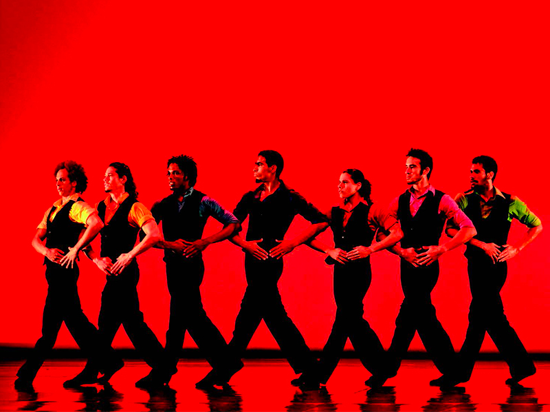 danzatori in fila per mano, sfondo di luce rossa