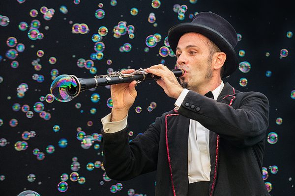 uomo vestito da maga suona un clarino tra le bolle