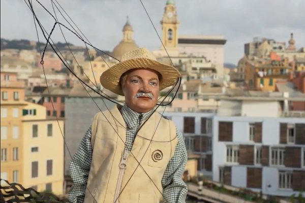 marionetta di uomo con sulllo sfondo la città di Genova