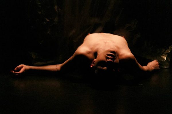 in uno spazio buio viene immortalata in penombra la danzatrice nuda col viso in primo piano.