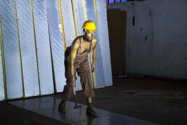 il danzatore è vestito come un minatore e indossa un casco giallo da cantiere. Il corpo e il viso sporchi di fuliggine. In mano tiene un grosso martello.