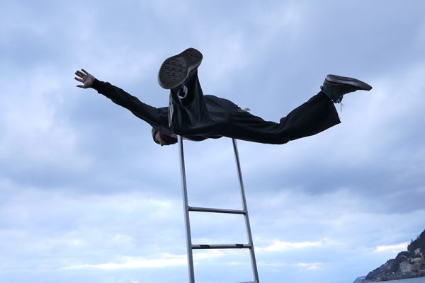 danzatore sdraiato in equilibrio su una scala a pioli